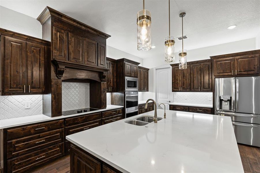 Kitchen featuring dark brown cabinets, backsplash, stainless steel appliances, pendant lighting, and recessed lighting Kitchen featuring dark brown cabinets, backsplash, stainless steel appliances, pendant lighting, and recessed lighting