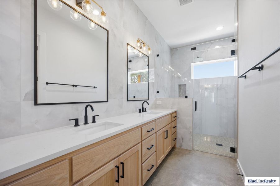 Full bath featuring double vanity, a marble finish shower, concrete floors, and recessed lighting