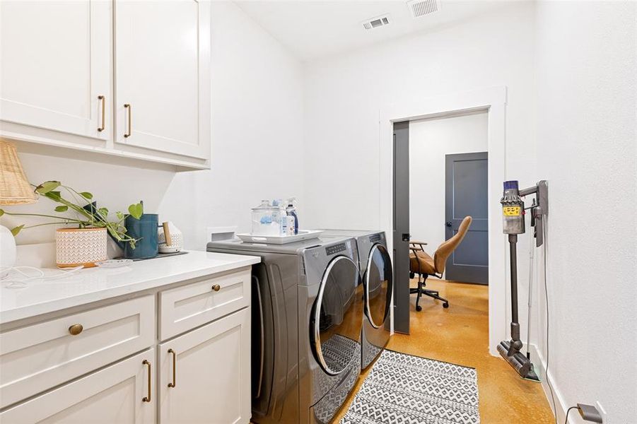 Dedicated laundry area featuring white shaker-style cabinetry with brass hardware, a light-toned countertop, and light-colored walls Dedicated laundry area featuring white shaker-style cabinetry with brass hardware, a light-toned countertop, and light-colored walls