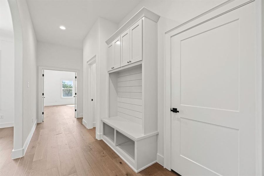 Mudroom with arched walkways, baseboards, light wood-style floors, and recessed lighting