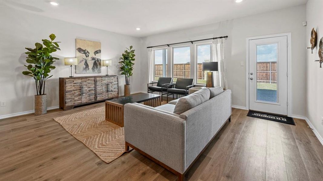 The living room features light-colored flooring, recessed lighting, and large windows that provide views of the outdoors The living room features light-colored flooring, recessed lighting, and large windows that provide views of the outdoors