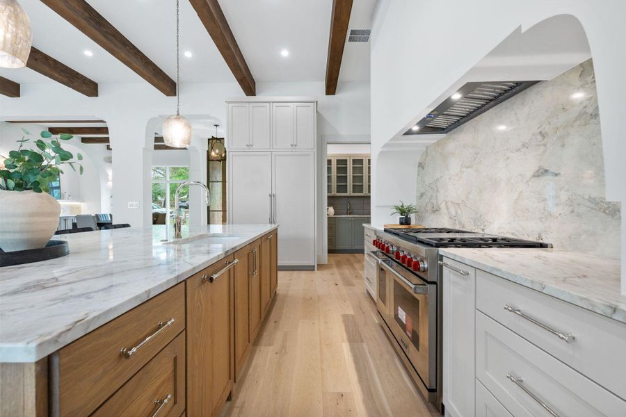 Kitchen with light stone counters, range with two ovens, arched walkways, light wood-type flooring, and recessed lighting Kitchen with light stone counters, range with two ovens, arched walkways, light wood-type flooring, and recessed lighting