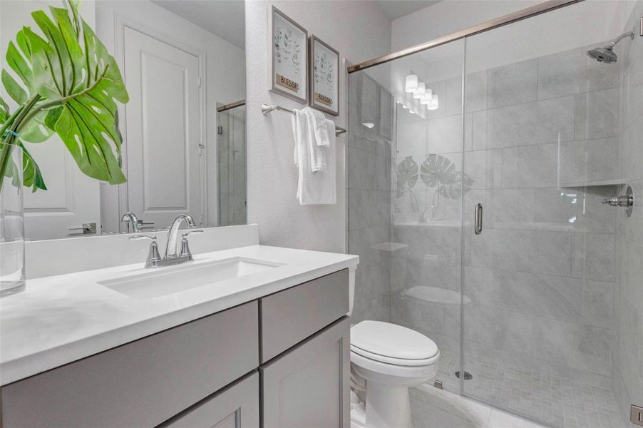 Bathroom features a sleek vanity with a white countertop, a glass-enclosed shower with light gray tiles, and bright lighting. Bathroom features a sleek vanity with a white countertop, a glass-enclosed shower with light gray tiles, and bright lighting.