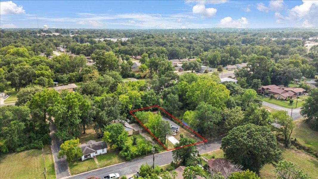 Aerial view of property and surrounding area with property parcel outlined and a forest