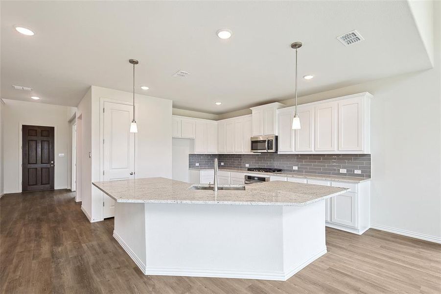 Kitchen with a center island with sink, sink, light wood-type flooring, and white cabinets