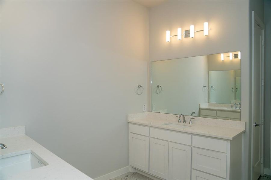 Bathroom featuring a dual vanity with white cabinetry and light-colored countertops, undermount sinks, a large wall-mounted mirror, and a contemporary four-light fixture Bathroom featuring a dual vanity with white cabinetry and light-colored countertops, undermount sinks, a large wall-mounted mirror, and a contemporary four-light fixture