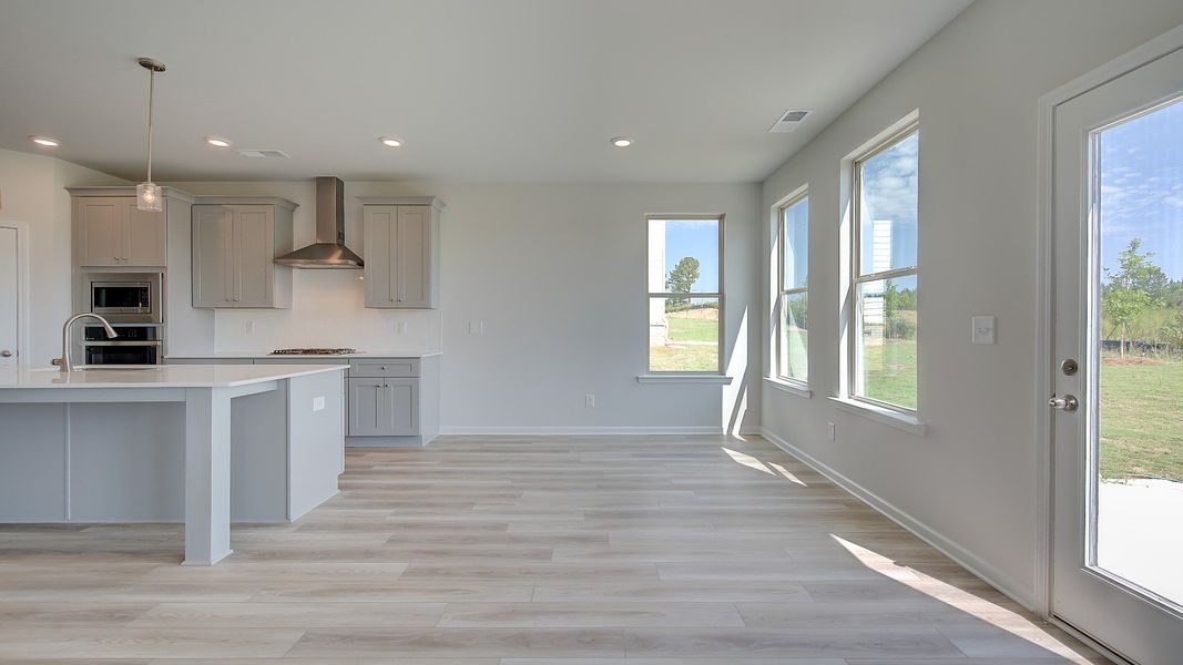 Bright breakfast room connected to kitchen with LVP flooring and view of covered porch in the Clarity at Brighton.