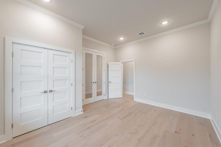 Unfurnished bedroom with french doors, light wood-style flooring, crown molding, recessed lighting, and a closet