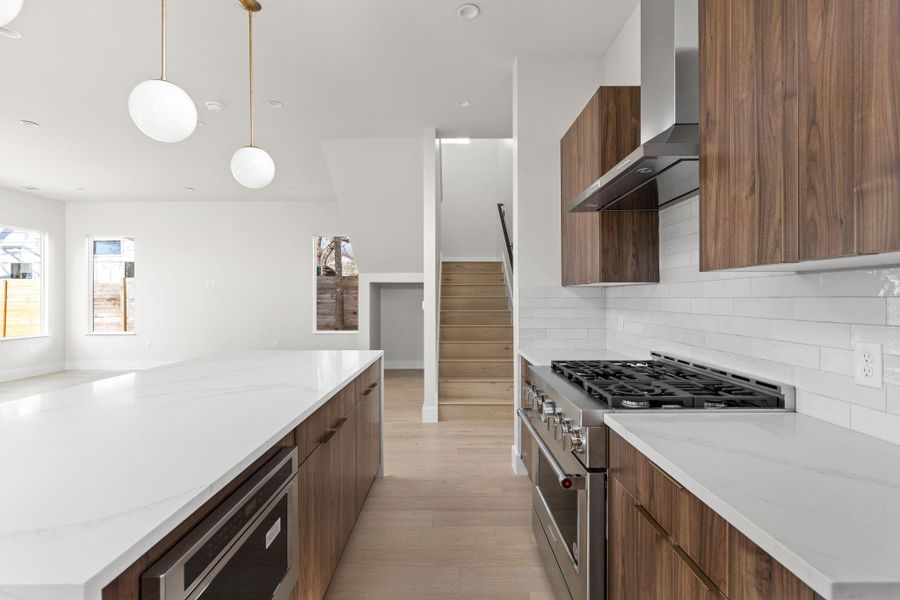 Kitchen with high end range, dishwasher, modern cabinets, and wall chimney exhaust hood