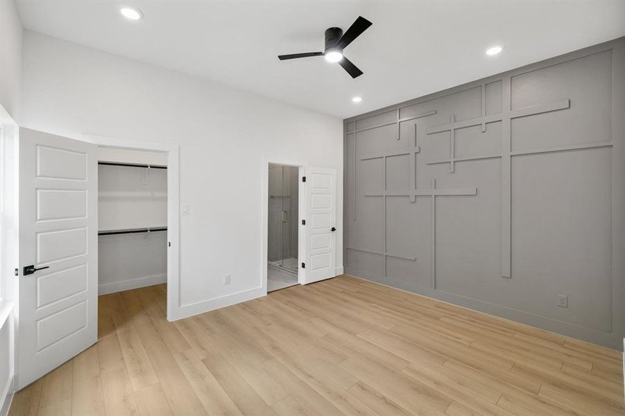 Unfurnished bedroom with light wood finished floors, a spacious closet, ceiling fan, and recessed lighting