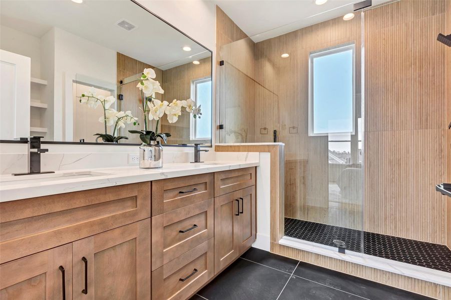 Elegant main bathroom featuring a glass-enclosed shower, dual sinks, and a large vanity mirror. Plus, plenty of cabinet storage for all your essentials. Elegant main bathroom featuring a glass-enclosed shower, dual sinks, and a large vanity mirror. Plus, plenty of cabinet storage for all your essentials.