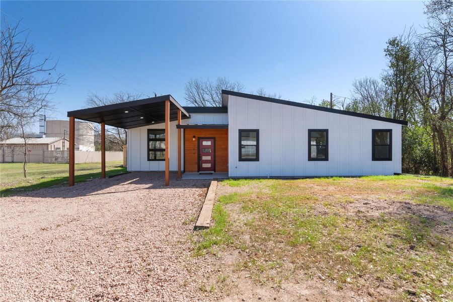 View of front of property featuring a carport, board and batten siding, and fence