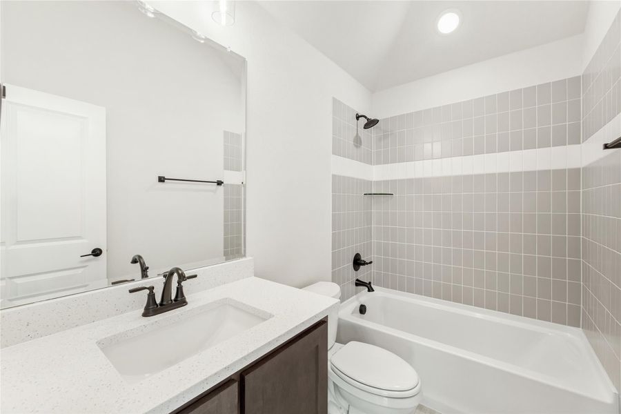 Bathroom with quartz vanity, white tub, and gray tiled shower surround with dark bronze fixtures Bathroom with quartz vanity, white tub, and gray tiled shower surround with dark bronze fixtures