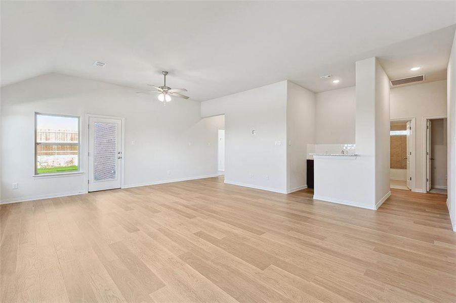 Unfurnished living room featuring light wood-type flooring, ceiling fan, and vaulted ceiling