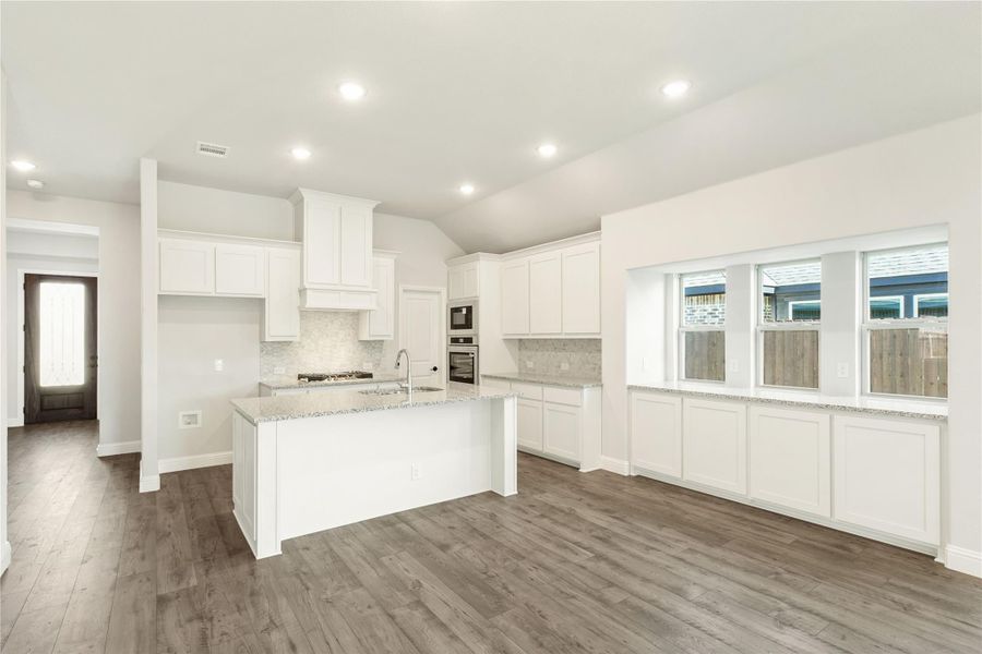 Open kitchen with white cabinets, center island, granite countertops, and dark hardwood floors