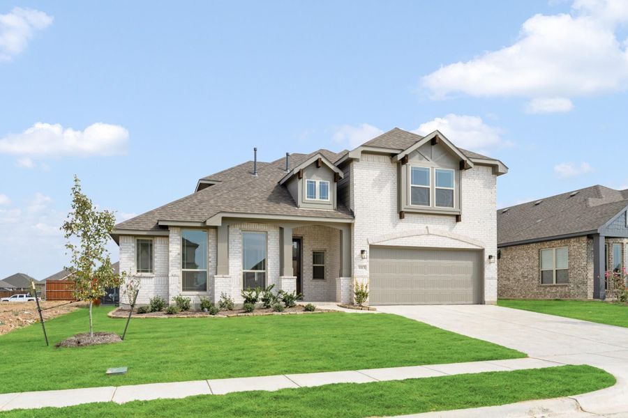 Two-story home with white brick exterior, two-car garage, and green front lawn