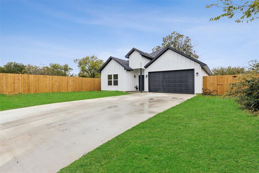 Modern farmhouse featuring a garage and a front yard