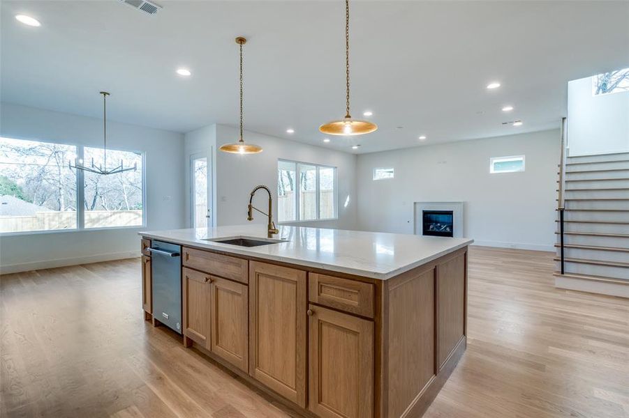 Kitchen with sink, hanging light fixtures, an island with sink, a healthy amount of sunlight, and light hardwood / wood-style floors