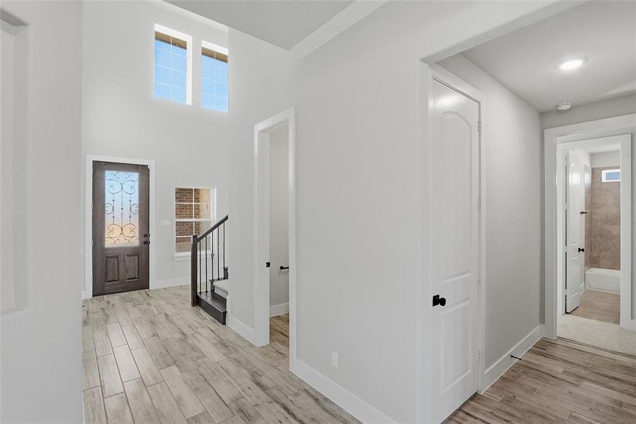 Foyer featuring light wood-style flooring, a towering ceiling, and stairway