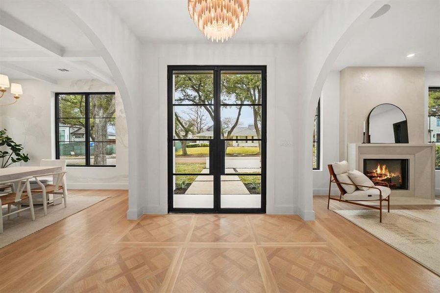 Entryway with a chandelier, parquet floors, arched walkways, a warm lit fireplace, and beam ceiling Entryway with a chandelier, parquet floors, arched walkways, a warm lit fireplace, and beam ceiling