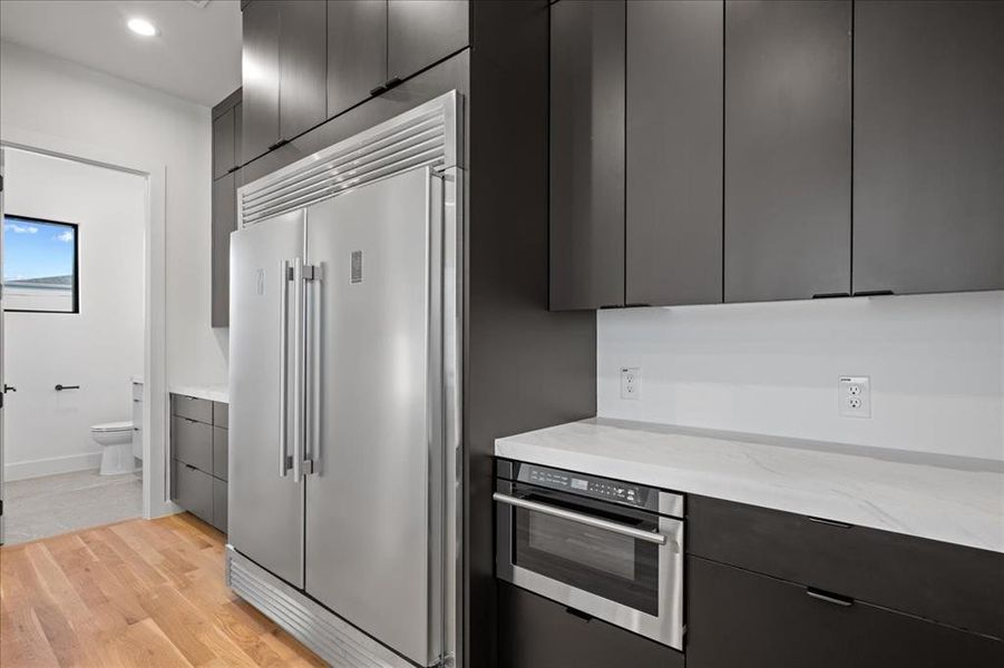 Kitchen featuring appliances with stainless steel finishes, light wood finished floors, modern cabinets, light stone countertops, and recessed lighting Kitchen featuring appliances with stainless steel finishes, light wood finished floors, modern cabinets, light stone countertops, and recessed lighting