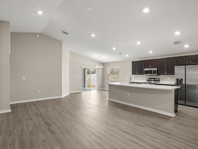 Enjoy a sunny, open-concept living area with volume ceilings and LVP flooring.