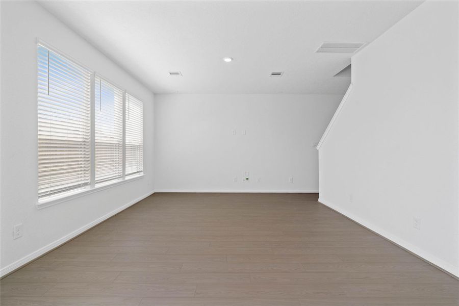 This bright Great Room offers a spacious layout ideal for both relaxing evenings and lively gatherings. Designed for comfort and connection, it features Bandera vinyl plank flooring, large windows with blinds, high ceilings, recessed lighting, and seamless access to the stunning kitchen and dining—perfect for everyday living and entertaining alike.