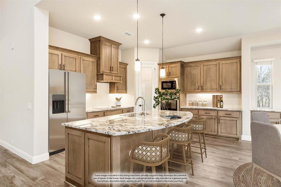 Kitchen with large granite island, tan wood cabinets, stainless steel refrigerator, and hardwood floors Kitchen with large granite island, tan wood cabinets, stainless steel refrigerator, and hardwood floors