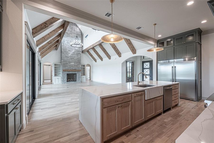 Kitchen with open floor plan, light stone countertops, arched walkways, a chandelier, and stainless steel appliances Kitchen with open floor plan, light stone countertops, arched walkways, a chandelier, and stainless steel appliances
