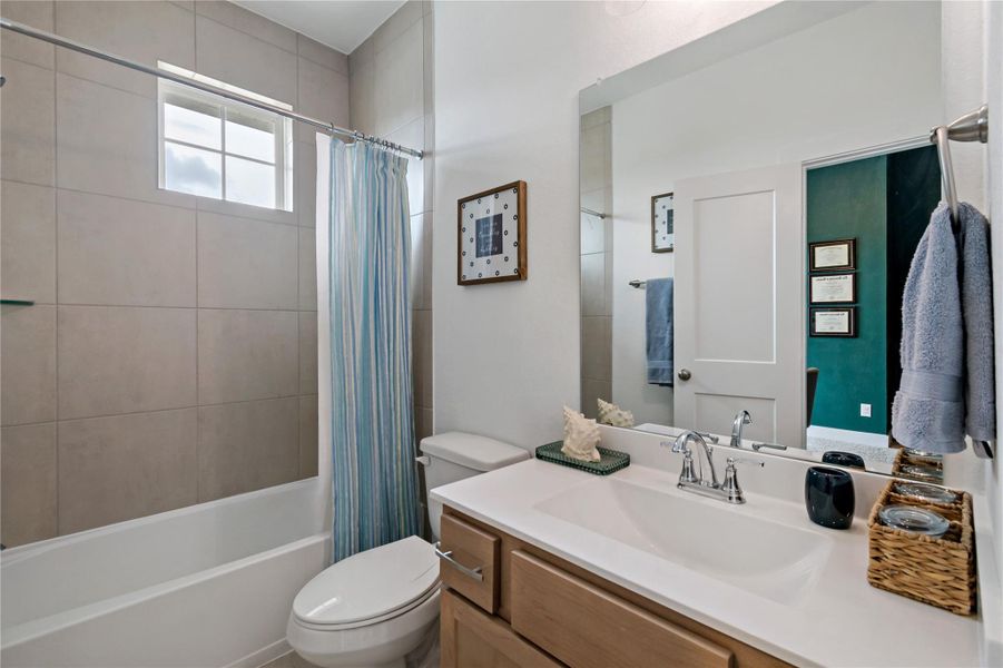 Bright and modern bathroom featuring a tiled shower-tub combo, sleek vanity with ample storage, and a large mirror enhancing the sense of space. Bright and modern bathroom featuring a tiled shower-tub combo, sleek vanity with ample storage, and a large mirror enhancing the sense of space.