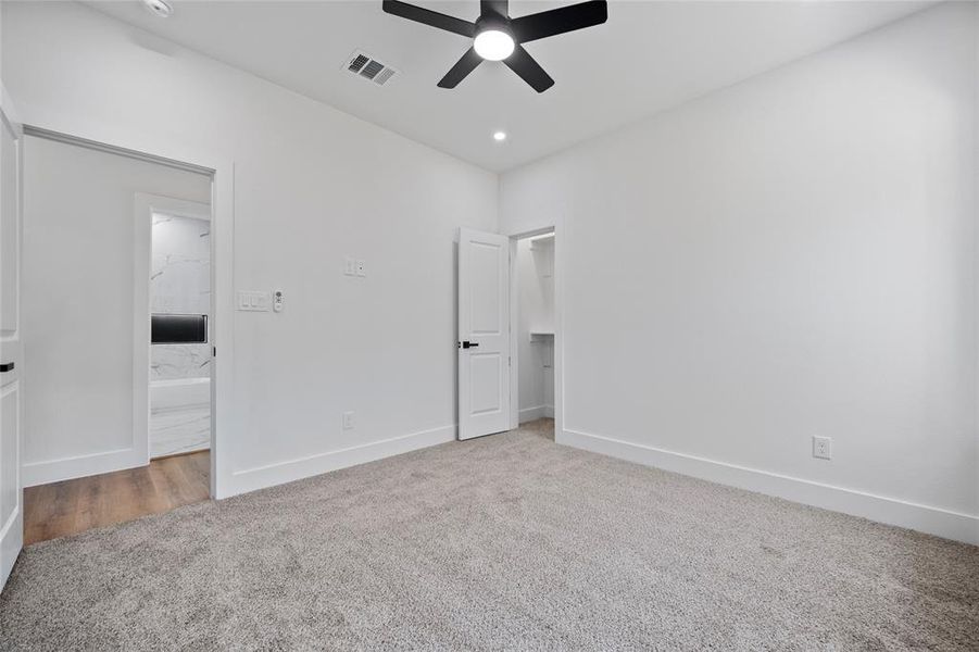 Unfurnished bedroom featuring ceiling fan, carpet floors, and connected bathroom