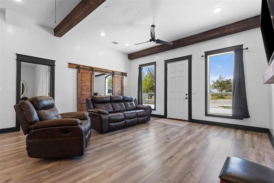 Living area featuring a barn door, beam ceiling, recessed lighting, a ceiling fan, and light wood-style flooring Living area featuring a barn door, beam ceiling, recessed lighting, a ceiling fan, and light wood-style flooring