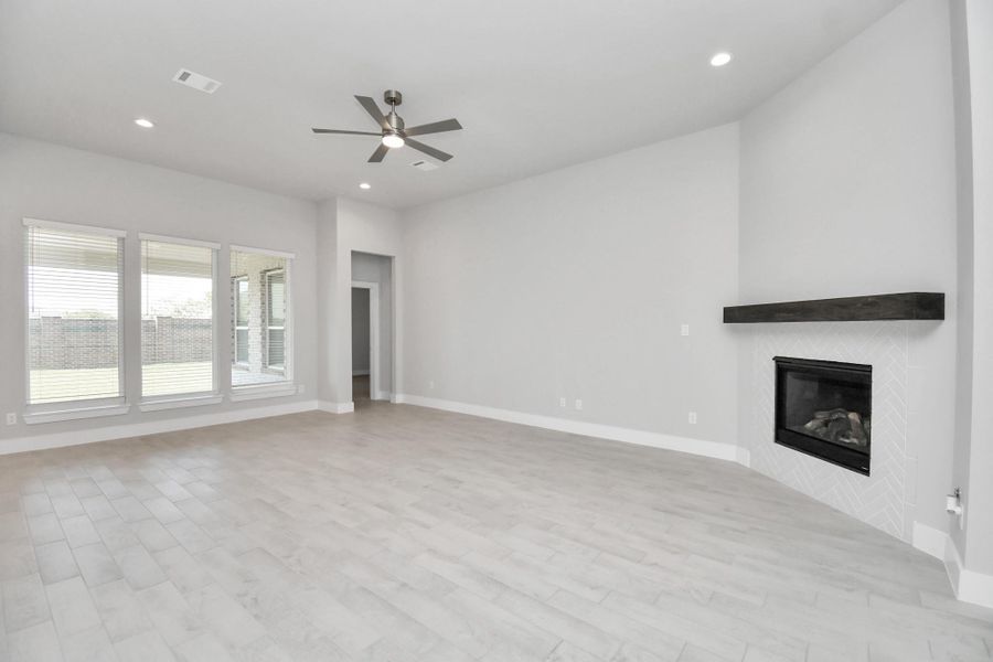 Family room flooded with natural light through the expansive windows.  The premium tile flooring adds a touch of luxury to the space, creating the perfect setting for relaxing moments and cherished gatherings with loved ones. Sample photo of completed home with similar floor plan. Actual colors and selections may vary.