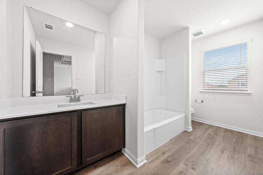 Full bathroom with hardwood / wood-style floors, vanity, toilet, and shower / washtub combination