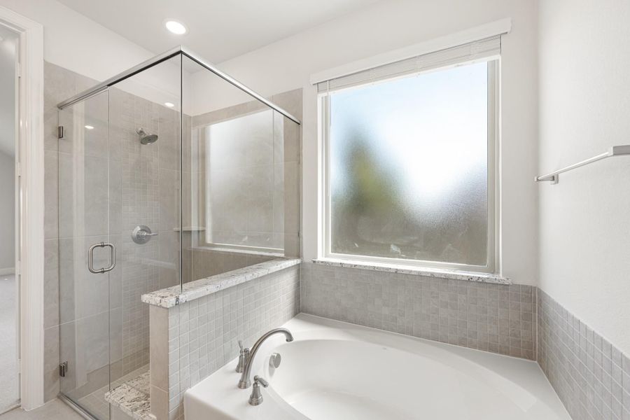 Bathroom with soaking tub, glass-enclosed shower, gray tile walls, and frosted privacy window