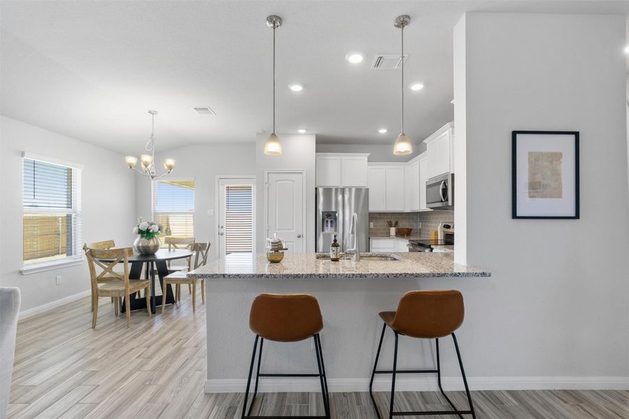 Kitchen with decorative light fixtures, white cabinetry, decorative backsplash, a peninsula, and a breakfast bar area