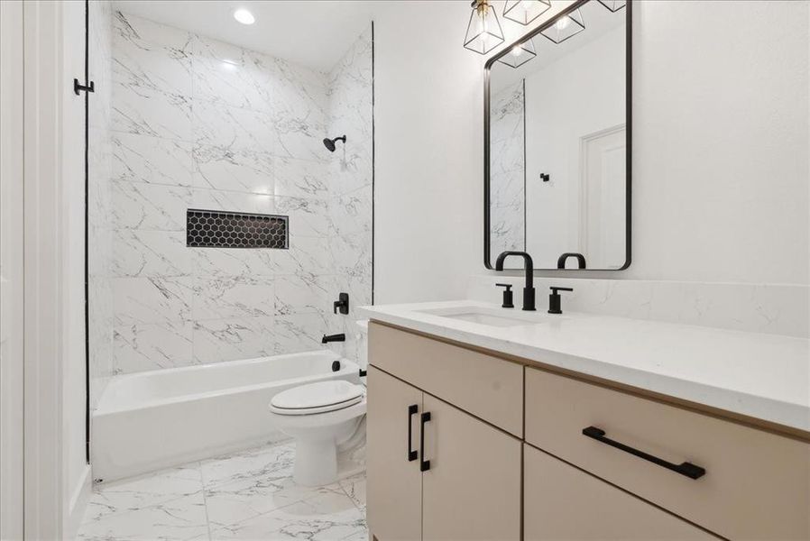 Full bathroom with vanity, tiled shower / bath combo, and toilet