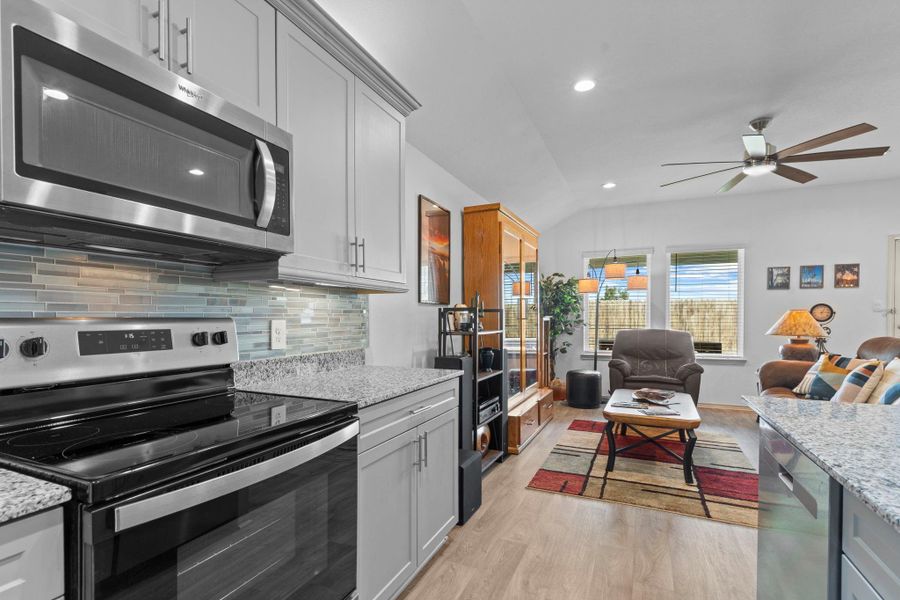 Gorgeous open concept family room flows effortlessly from the kitchen, smooth top range for easy cleaning! Soaring ceilings, abundant recessed lighting under and above the beautiful shaker cabinets, and easy-care wood-look vinyl plank flooring — perfect for relaxing or entertaining guests. Gorgeous open concept family room flows effortlessly from the kitchen, smooth top range for easy cleaning! Soaring ceilings, abundant recessed lighting under and above the beautiful shaker cabinets, and easy-care wood-look vinyl plank flooring — perfect for relaxing or entertaining guests.