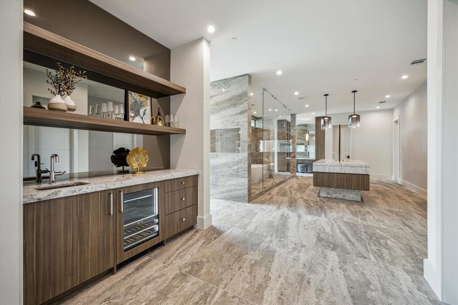 A morning bar offers ultimate convenience with amenities such as a Jennair 24” wide Energy Star rated beverage center, River White countertops, a Brizo single hole bathroom sink faucet in brilliance brushed nickel, and a Thompson Traders dual mount hammered stainless steel sink.