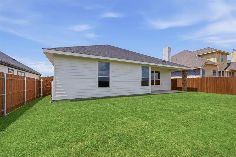 Expansive backyard featuring a manicured lawn, full wood fencing, and a concrete patio Expansive backyard featuring a manicured lawn, full wood fencing, and a concrete patio