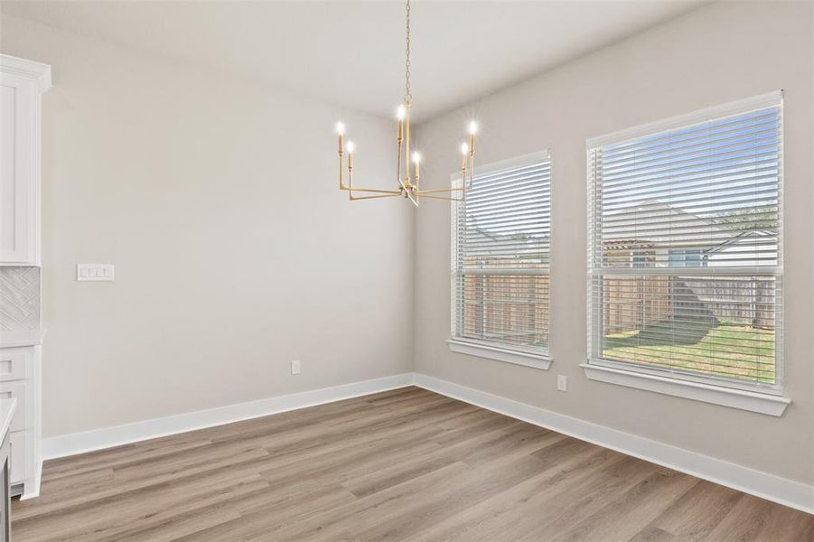 Unfurnished dining area with hanging lights and light wood-style floors