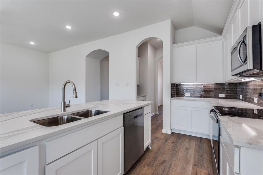 Kitchen with white cabinets, appliances with stainless steel finishes, dark wood-type flooring, and sink