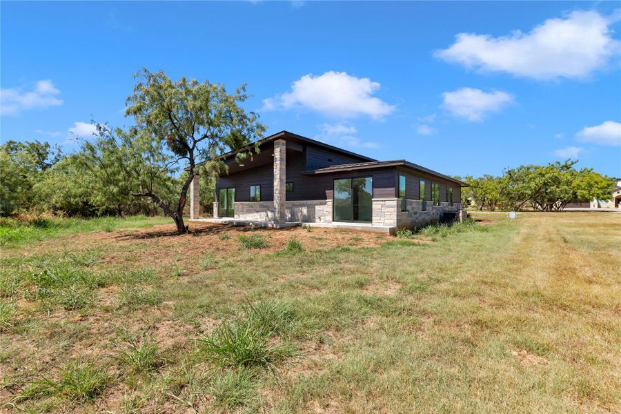 Clean modern architectural lines blend wood and stone siding under a wide clear sky.