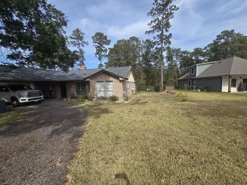View of front facade with asphalt driveway, a front lawn, an attached carport, brick siding, and a chimney View of front facade with asphalt driveway, a front lawn, an attached carport, brick siding, and a chimney