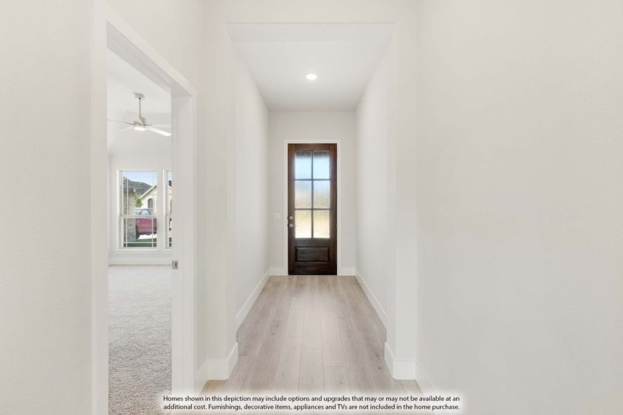 Narrow entryway hallway with light wood floors, white walls, and dark wood front door with glass panels Narrow entryway hallway with light wood floors, white walls, and dark wood front door with glass panels