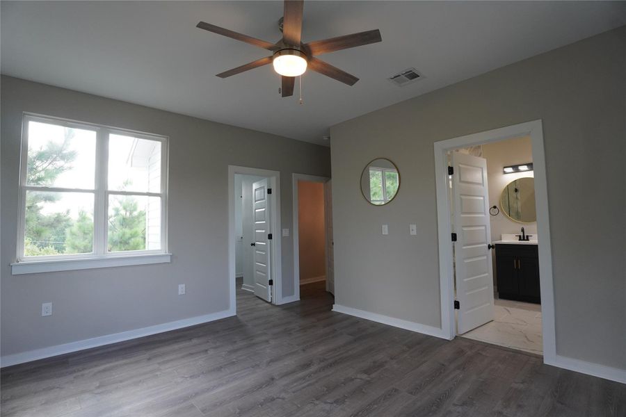 Primary bedroom featuring wood finished floors, plenty of natural light, and ceiling fan