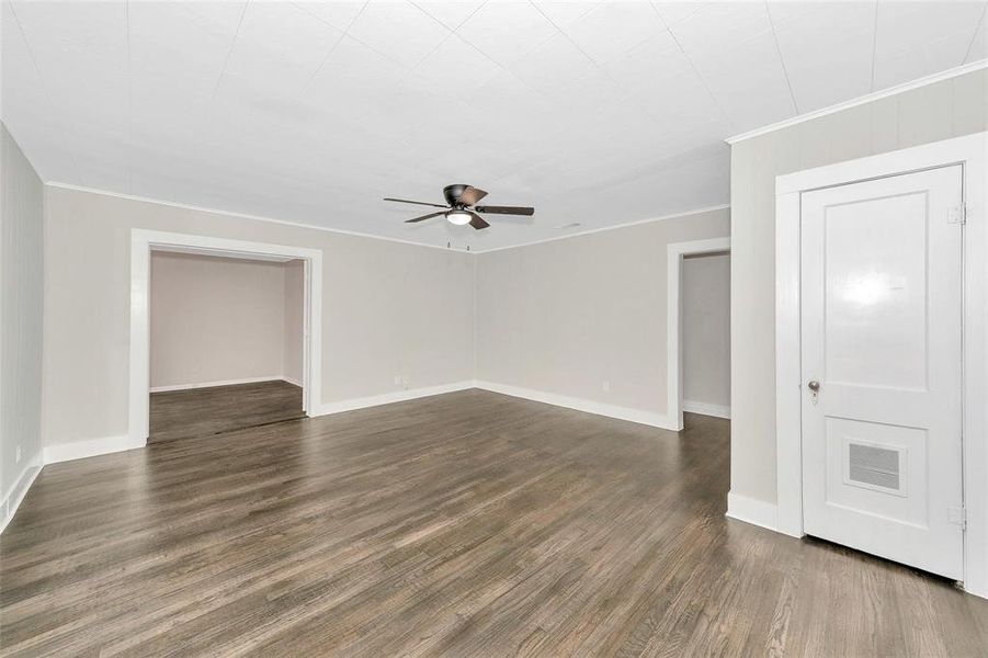 Unfurnished room with ceiling fan, dark wood-type flooring, and ornamental molding Unfurnished room with ceiling fan, dark wood-type flooring, and ornamental molding