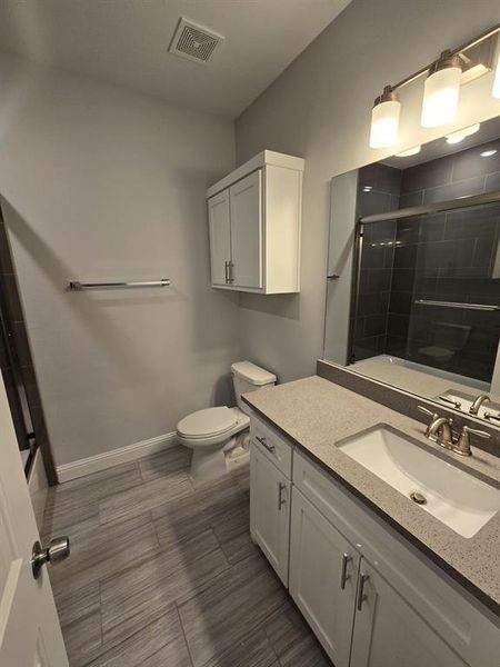 Bathroom featuring a shower with shower door, toilet, and vanity