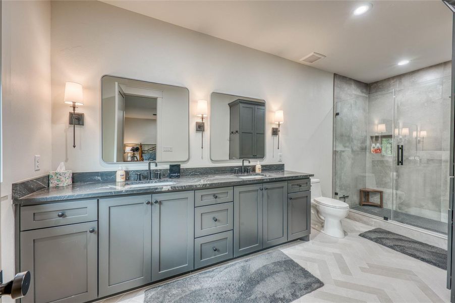 Dual vanity featuring shaker-style cabinetry, dark countertops, and rectangular framed mirrors
