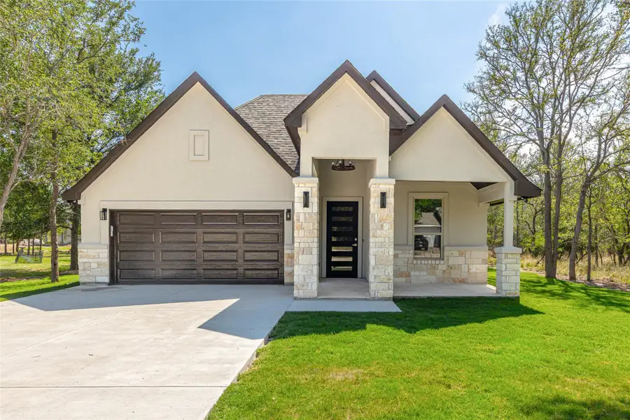 View of front of home featuring stone siding, stucco siding, concrete driveway, a front yard, and a porch